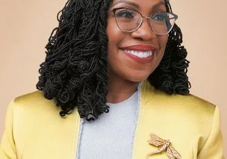 A woman in a yellow jacket and glasses.